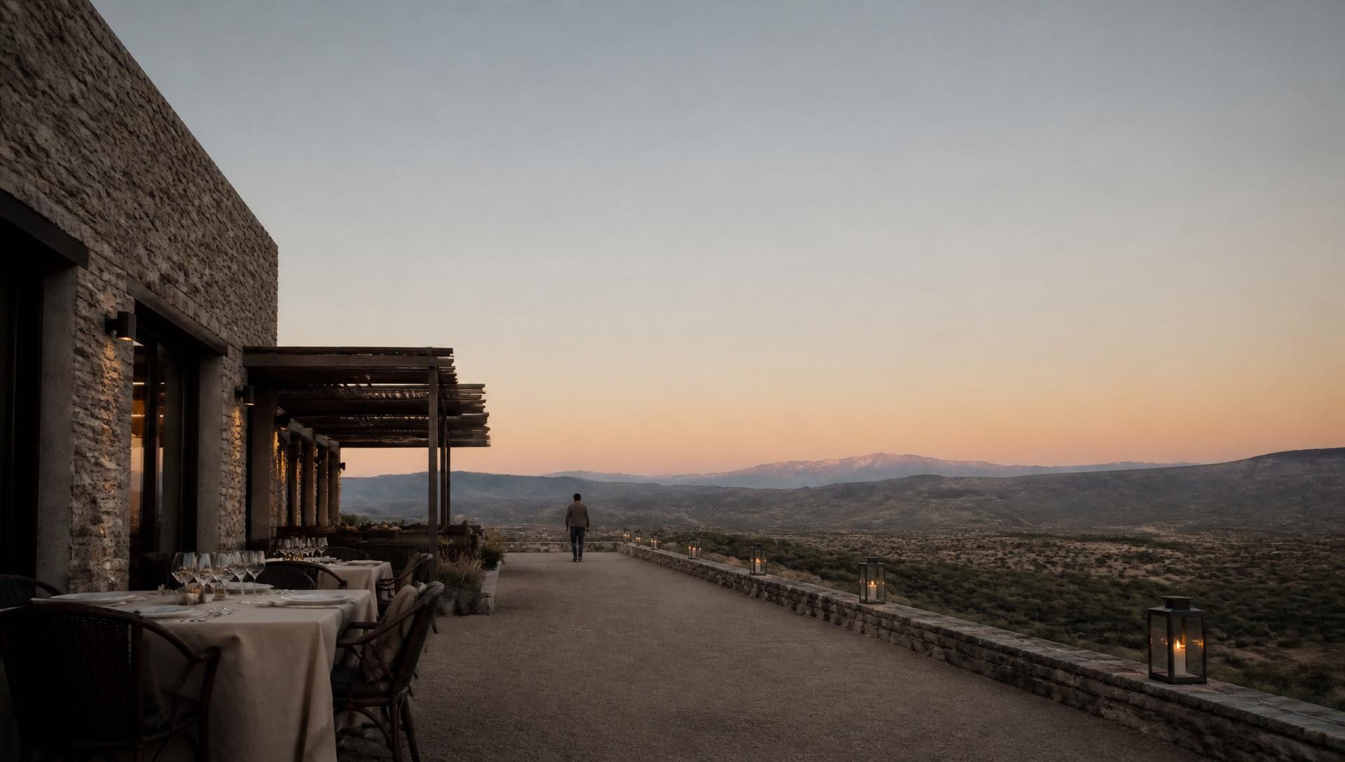 Terraza de un hotel boutique argentino al atardecer, con una mesa servida y la montaña al fondo
