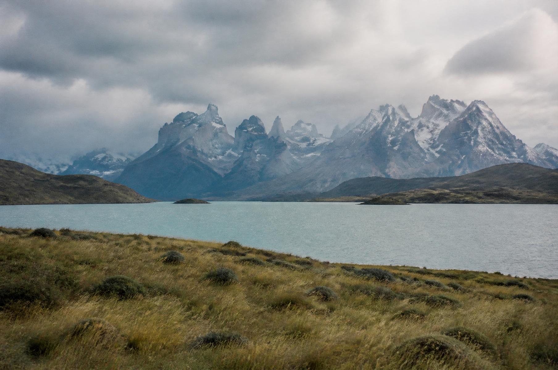 Viajeros recorriendo la galería de una bodega boutique con viñedos y la cordillera al fondo